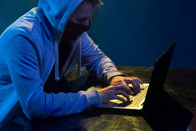 hooded-computer-hacker-stealing-information-with-laptop_155003-9013
