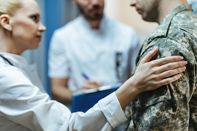 Close-up female doctor consoling military man in the hospital.